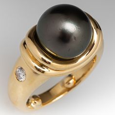 This gorgeous ring is centered with one (1), post set, cultured Tahitian pearl. The shoulders of the ring are each accented with one (1), flush set, round brilliant cut diamond. The ring measures 11.0mm at the top, rises 11.9mm above the finger, tapering to 3.1mm wide and 1.7mm thick at the base of the shank. The ring currently fits like a size 5 with sizing bar. Luxury Heirloom Pearl Ring With High Luster, Elegant Pearl Ring With Bezel Setting For Formal Occasions, Elegant Pearl Ring With Bezel Setting For Formal Events, Elegant Formal Pearl Ring With Bezel Setting, Elegant Oval Pearl Ring With Bezel Setting, Classic Pearl Ring With Single Diamond For Formal Occasions, Luxury Tahitian Pearl Ring In Yellow Gold, Classic Formal Pearl Ring With Single Diamond, Luxury Yellow Gold Tahitian Pearl Ring