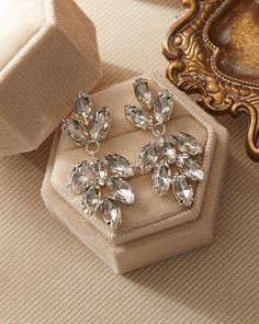 Add both beauty and sparkle to your wedding day look with our Angelina Wedding Earrings. Crafted with marquise shaped crystals in a floral leaf design, these earrings will become a forever favorite. Crystal gemstones 1.5" length x 0.5" width Hypoallergenic, lead-free & nickel-free Shown with Monica Comb, sold separately. Style #4300 Glamorous Crystal Diamond Earrings For Wedding, Dazzling Diamond White Crystal Earrings With Sparkling Stones, Dazzling Diamond White Earrings With Sparkling Stones, Glamorous Chandelier Earrings With Sparkling Stones For Anniversary, Glamorous Sparkling Chandelier Earrings For Anniversary, Silver Sparkling Crystal Earrings, Dazzling Crystal Earrings With Sparkling Stones, Elegant Diamond White Crystal Earrings, Glamorous Diamond White Bridal Earrings With Sparkling Stones