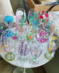 a table topped with lots of wine glasses on top of a white table covered in flowers