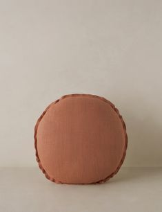 a round cushion with braiding on the side and a white wall in the background