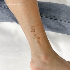 a woman's foot with a small flower tattoo on her left ankle and right leg