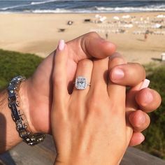 two people holding hands with the beach in the background