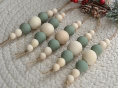 several wooden beads are lined up next to pine cones and evergreen needles on a white tablecloth