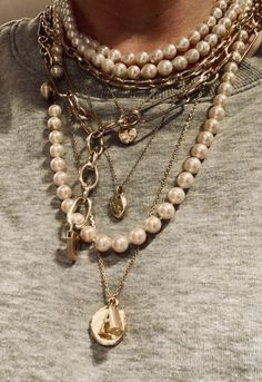 a close up of a person wearing multiple necklaces