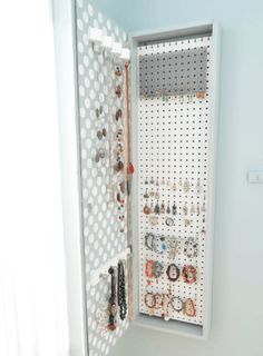 a jewelry organizer in the corner of a white room with polka dot wallpaper on it