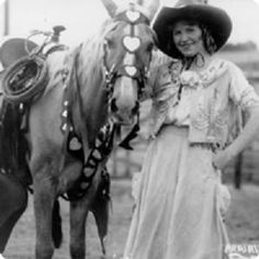 a woman standing next to a horse wearing a cowboy hat