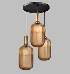 three glass pendants hanging from a ceiling fixture in gold and black color, with one light