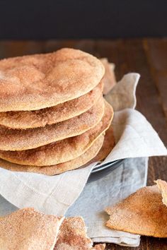 a stack of pancakes sitting on top of a wooden table next to a knife and napkin