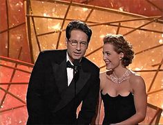 a man in a tuxedo standing next to a woman in a black dress