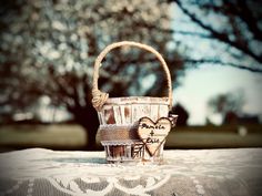 a basket with two hearts on it sitting on top of a lace covered tablecloth