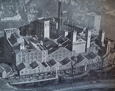 an old black and white photo of a city with buildings in the middle of it