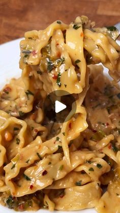 a spoon full of pasta and sauce on a white plate with a wooden table in the background