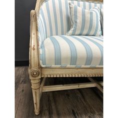 an old chair with blue and white striped fabric on it's armrests