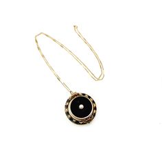 "Designed to commemorate a lost loved one, this historic flip fob pendant is accented with a 5mm seed pearl set into the yellow gold-filled metal. The metal is decorated with black enamel in mid-Victorian designs. The back compartment is filled with dark brown fabric and could hold a small keepsake. Dripping in Victorian elegance, this would make a wonderful addition to your antique collection. The necklace is in good antique condition with some signs of wear. The black background of the front h Vintage Charm Pendant Necklace As Keepsake, Victorian Necklaces With Detachable Pendant, Antique Oval Jewelry With Black Enamel, Victorian Necklace With Detachable Pendant, Antique Oval Black Enamel Jewelry, Heirloom Necklace With Detachable Pendant, Heirloom Yellow Gold Jewelry With Black Enamel, Antique Necklaces With Detachable Round Pendant, Antique Necklace With Detachable Round Pendant