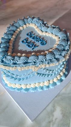 a heart shaped cake with blue icing and white frosting on it's sides