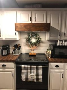 a black stove top oven sitting inside of a kitchen next to wooden counter tops and white cabinets