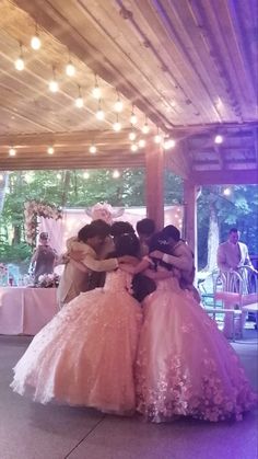 three women in dresses are hugging each other on the dance floor at a wedding reception