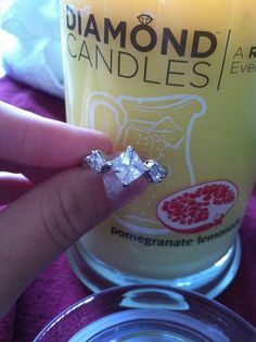 a person holding up a ring on top of a glass filled with liquid and ice