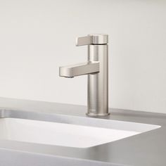 a bathroom sink with a faucet in the middle and a white wall behind it