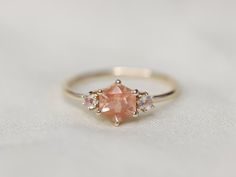 an engagement ring with a pink diamond and three white diamonds on it's side