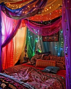 a bed covered in lots of colorful lights and drapes over it's head