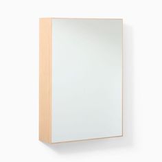 a mirror mounted to the side of a white wall next to a wooden cabinet with drawers