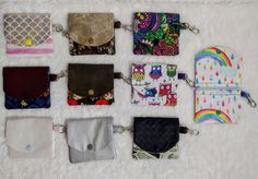 six different purses are lined up on a white furnishce surface, one is open and the other has an empty wallet in it