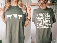 Hello friend! This retro "Buy me Cows and Tell me You Don't Trust the Government" front and back design is made on a Comfort Colors® - Unisex short sleeve crew neck tee. You'll be sure to LOVE the quality and its soft-washed, garment-dyed, extra cozy fabric! The double-needle stitching throughout the tee makes it highly durable while the lack of side-seams helps the shirt retain its tubular shape. It's the perfect tee for all your homesteading activities or to sport at your local farmer's market Farm Tshirt Ideas, Homesteading Activities, Homestead Compound, 4h Shirts, Homestead Shirt, Farmers Market Shirt, Farm Clothes, Cute Shirt Designs, Gifts For Farmers