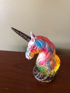 a colorful unicorn figurine sitting on top of a wooden table