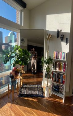 a person standing in the doorway of a room with bookshelves and plants on it