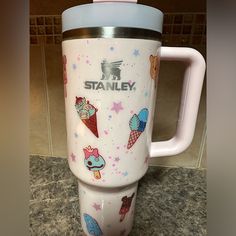 a white travel mug with an ice cream cone and stars on it sitting on a counter