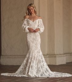 Introducing the Aspen Dress—your one-of-a-kind wedding gown brought to life. This off-the-shoulder wedding dress with sleeves is designed to make you feel like the most unique and beautiful bride. Crafted from luxurious textured cord cotton lace, it combines comfort with elegance. The off-the-shoulder neckline and dipped lower back create a stunning silhouette, while the voluminous puffed sleeves add a touch of romance.

The trumpet-fitted silhouette features a princess seaming down the front and back for a flattering fit, complemented by a long, graceful train that ensures your entry is a WOW factor. The bodice, enhanced with boning and bra cups, provides the perfect support, allowing you to move on your special day with utmost confidence and ease. Hand-cut appliqué adorns the neckline, b Off The Shoulder Lace Aline Wedding Dress, Boho Trumpet Wedding Dress, Fitted Lace Wedding Dress With Sleeves Open Backs, Off The Shoulder Wedding Dress With Sleeves, Vintage Lace Wedding Dress With Sleeves, October Wedding Dresses, Fitted Lace Wedding Dress, Off The Shoulder Wedding Dress, Wedding Dress With Sleeves