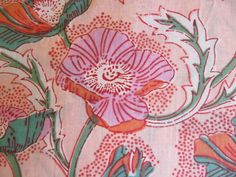 a pink and green floral print fabric with orange flowers on it's side,