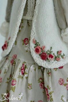 a close up of a doll's dress with flowers on the bottom and sleeves