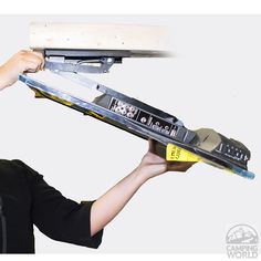 a woman holding up a laptop computer on top of a keyboard tray with a yellow tape around it