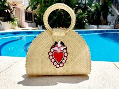 a straw purse sitting next to a pool with a heart decoration on it stock photo