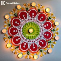 an intricate rangoli design with candles on the wall