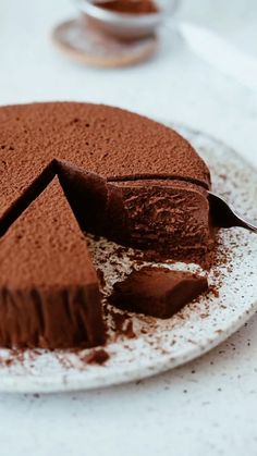 a chocolate cake on a plate with one slice cut out and the rest half eaten