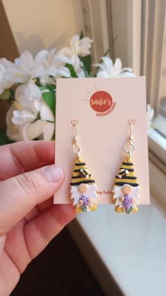 a pair of yellow and white earrings with flowers on them in front of a window