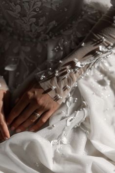 a close up of a person's hands on a wedding dress