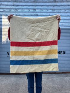 a person holding up a large blanket in front of a garage door