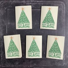 four cards with green christmas trees on them sitting on a black tray next to each other