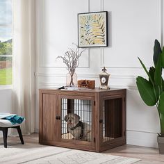 a dog is sitting in its cage next to a potted plant on the floor