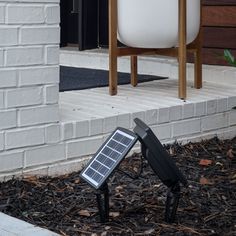 there is a solar panel on the ground in front of a chair and potted plant