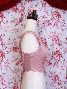 Be the star of the show with this gorgeous Renaissance to Baroque Era corset, this time in a special ballet pink satin! This piece features hand-sewn mauve and ivory rosette adornments, pink satin ribbon finishes, adjustable straps, and a classic Tudor Era design. Style it over a delicate dress or blouse with a puffy skirt for the perfect historically-inspired ballerina look. Sizing: ✧IN✧ Bust Waist S 30-34 Inches 24-28 Inches M 34-38 Inches 28-32 Inches L 38-42 Inches 30-34 Inches XL 40-44 Inches 36-40 Inches ✧CM✧ Bust Waist S 75-85 CM 60-70 CM M 85-95 CM 70-80 CM L 95-105 CM 75-85 CM XL 100-110 CM 90-100 CM Materials:10% Elastane 90% Polyester Care:Gently hand wash or dry clean only. Air dry only, hang or dry flat. Elegant Fitted Pink Corset, Feminine Fitted Pink Corset, Pink Feminine Underbust Corset, Pink Underbust Feminine Corset, Feminine Pink Underbust Corset, Pink Fitted Underbust Corset, Fitted Pink Underbust Corset, Fitted Underbust Pink Corset, Underbust Satin Corset With Satin Finish