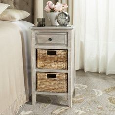 a nightstand with two baskets and a clock on it next to a bed in a bedroom