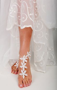 a bride's barefoot sandals are adorned with white flowers