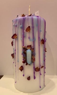 a white candle with purple and blue drips on it