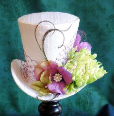 This spring bridal mini top hat is covered with all-time classic white silk shantung. This playful fascinator is trimmed with purple veil around the crown of the hat, along with a striking dahlia flower and hydrangea blossoms in violet and green shades...some of them have a rhinestone sparkling secret in the middle! A spray of hand-curled peacock feathers was added here and there just to bring in some extra playfulness! This mini top hat is fully lined with satin and attaches to the head with th Spring Wedding Flower, Bridal Mini, Purple Cocktails, Pink Bridesmaids, Tea Hats, Mad Hatter Party, Victorian Hats, Mad Hatter Hats, Steampunk Hat