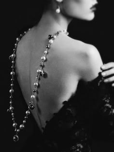 black and white photograph of woman in evening dress with pearls on her neck, looking off to the side